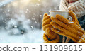 Gloved hands gently cradling a steaming cup of aromatic coffee outdoors. Warm cozy winter scene. Hot Mug of beverage in the wool mittens closeup. Warming drink at cold weather. Hike, camping concept 131909615