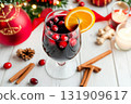 Hot red mulled wine with christmas spices, orange slice, anise and cinnamon sticks. One glass of mulled wine on white table with red checkered napkin with spices and fruits. Traditional Autumn drink 131909617