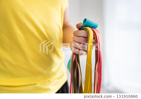 Sporty Man Holding Resistance Rubber Bands For Home Trainings Sporty Man Holding Resistance Rubber Bands For Home Trainings 131910860
