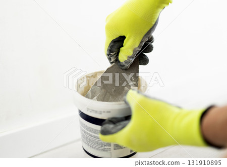 Worker Using A Spatula To Apply Wall Putty And Spackle Walls For A Smooth Finish 131910895
