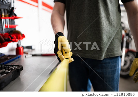 Worker Holding A Measuring Tape In Hands At The Workspace Worker Holding A Measuring Tape In Hands At The Workspace 131910896