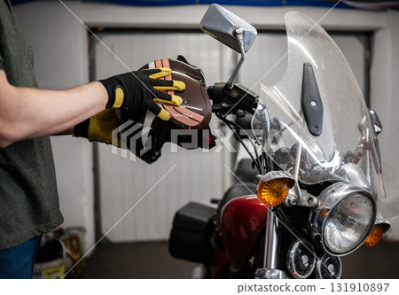 Man Wearing A Protective Moto Helmet Against A Classic Motorcycle In The Garage Man Wearing A Protective Moto Helmet Against A Classic Motorcycle In The Garage 131910897
