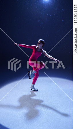 Female figure skater in pink outfit gliding gracefully in balanced one-leg spin on ice Female figure skater in pink outfit gliding gracefully in balanced one-leg spin on ice 131911215