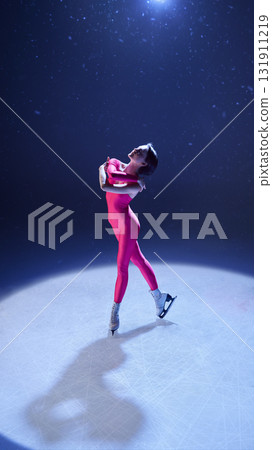 Female skater in pink bodysuit embracing herself in graceful emotional performance on ice 131911219