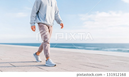 Man in sportswear walking along seaside promenade during golden hour for mindful fitness trend 131912168