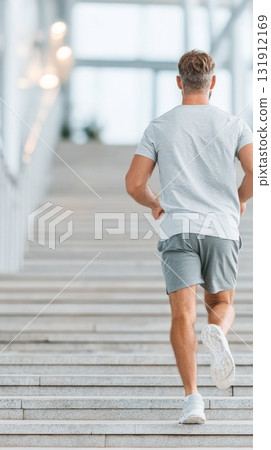 Man exercising while walking upstairs in a modern fitness environment with dynamic lighting Man exercising while walking upstairs in a modern fitness environment with dynamic lighting 131912169