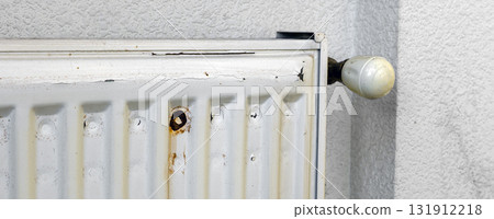 Corrosion on the metal surface of a heating radiator in a room.aged radiator battery. Corrosion on the metal surface of a heating radiator in a room 131912218
