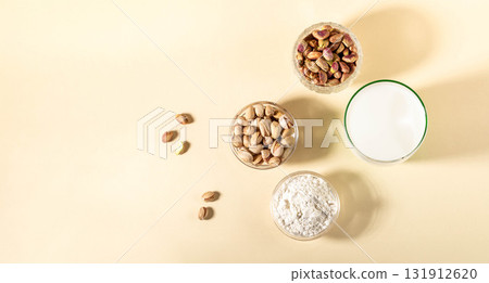 Pistachios, nut powdered milk, nut powder in glass containers on beige background Top view Banner Pistachios, nut powdered milk, nut powder in glass containers on beige background Top view Banner 131912620
