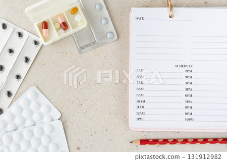 Flat lay with pill organizer, blister packs and medication plan sheet on beige background. Healthcare and pharmaceutical concept showing treatment, prevention and daily medicine schedule for patients 131912982
