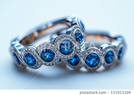 Luxurious pair of wedding rings with blue stones on a white background. Rococo-Renaissance style. 131913104
