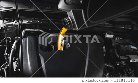 Golden motor oil being poured into car engine during maintenance service close up Golden motor oil being poured into car engine during maintenance service close up 131913116