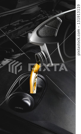 Close up of golden motor oil pouring from plastic container into car engine opening Close up of golden motor oil pouring from plastic container into car engine opening 131913119
