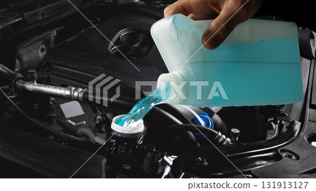Mechanic pouring blue washer fluid into car engine compartment macro view Mechanic pouring blue washer fluid into car engine compartment macro view 131913127