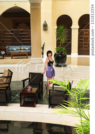 A slender woman in summer shorts in the lobby of a luxury hotel A slender woman in summer shorts in the lobby of a luxury hotel 131913354