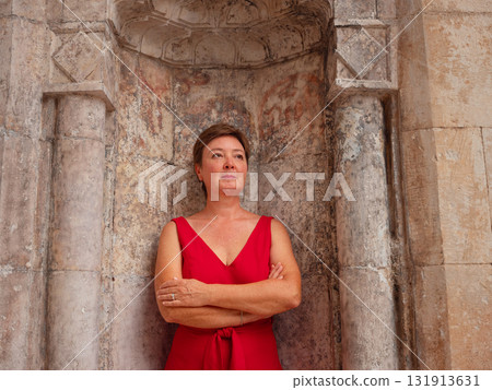 Woman in red dress walking narrow streets of old town Antalya during warm summer evening. Historic atmosphere and Mediterranean charm creates peaceful travel experience. near old mosque Woman in red dress walking narrow streets of old town Antalya during warm summer evening. Historic atmosphere and Mediterranean charm creates peaceful travel experience. near old mosque 131913631