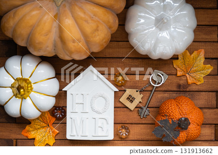 Cozy layout on a wooden background of slats with pumpkins, autumn leaves, a tiny house and keys - autumn mood, Halloween, housing, relocation, mortgage, insurance. Cozy layout on a wooden background of slats with pumpkins, autumn leaves, a tiny house and keys - autumn mood, Halloween, housing, relocation, mortgage, insurance. 131913662