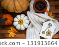 Cozy layout on a wooden background of slats with pumpkins, autumn leaves, a tiny house and keys - autumn mood, Halloween, housing, relocation, mortgage, insurance. 131913664
