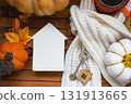 Cozy layout on a wooden background of slats with pumpkins, autumn leaves, a tiny house and keys - autumn mood, Halloween, housing, relocation, mortgage, insurance. 131913665