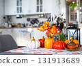 Decor of white classic kitchen with pumpkins, garlands, autumn bouquet with yellow leaves for Halloween and harvest. Autumn mood in home interior, modern loft style. real estate, insurance, mortgage 131913689