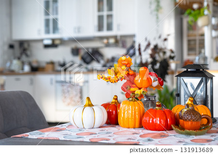 Decor of white classic kitchen with pumpkins, garlands, autumn bouquet with yellow leaves for Halloween and harvest. Autumn mood in home interior, modern loft style. real estate, insurance, mortgage 131913689