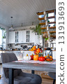 Decor of white classic kitchen with pumpkins, garlands, autumn bouquet with yellow leaves for Halloween and harvest. Autumn mood in home interior, modern loft style. real estate, insurance, mortgage 131913693