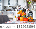 Cozy autumn decor on white kitchen with tiny house and keys, pumpkins, autumn leaves, autumn mood, Halloween, Harvest Festival, housing, relocation, mortgage, insurance. 131913694
