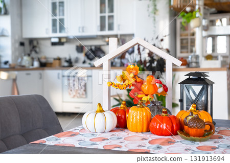 Cozy autumn decor on white kitchen with tiny house and keys, pumpkins, autumn leaves, autumn mood, Halloween, Harvest Festival, housing, relocation, mortgage, insurance. Cozy autumn decor on white kitchen with tiny house and keys, pumpkins, autumn leaves, autumn mood, Halloween, Harvest Festival, housing, relocation, mortgage, insurance. 131913694