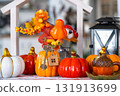Cozy autumn decor on white kitchen with tiny house and keys, pumpkins, autumn leaves, autumn mood, Halloween, Harvest Festival, housing, relocation, mortgage, insurance. 131913699