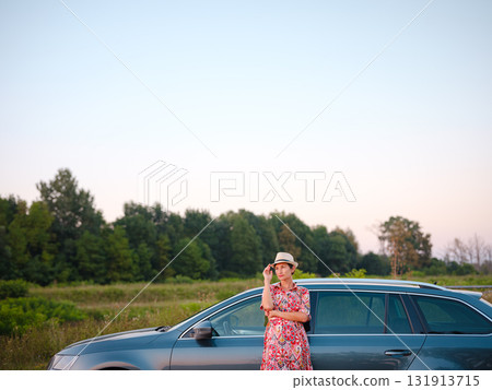 Traveler woman in red ethnic dress and hat drives car through scenic countryside of Croatia in summer. Surrounded by lush fields and forests, she enjoys peaceful and adventurous road trip 131913715
