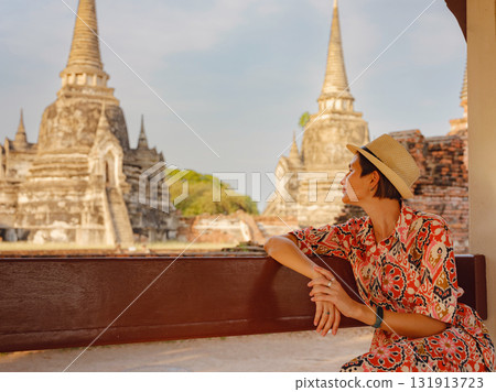 Young female tourist in dress exploring historic park of Ayutthaya, Thailand. Wat Phra Si Sanphet ancient temples and statues, she enjoys peaceful atmosphere and rich cultural heritage. Young female tourist in dress exploring historic park of Ayutthaya, Thailand. Wat Phra Si Sanphet ancient temples and statues, she enjoys peaceful atmosphere and rich cultural heritage. 131913723
