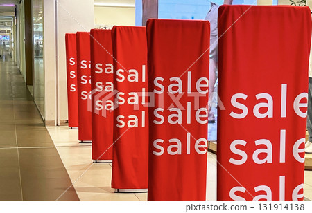Bright red sale banners attract shoppers in a busy mall 131914138