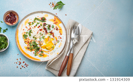 Turkish eggs cilbir, Middle Eastern style breakfast on blue background table top view, space for text 131914309