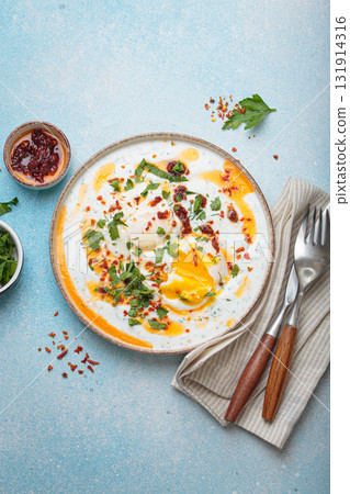 Turkish eggs cilbir, Middle Eastern style breakfast on blue background table top view Turkish eggs cilbir, Middle Eastern style breakfast on blue background table top view 131914316