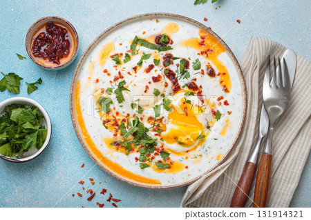 Turkish eggs cilbir, Middle Eastern style breakfast on blue background table top view Turkish eggs cilbir, Middle Eastern style breakfast on blue background table top view 131914321