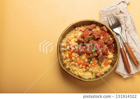 Moroccan couscous with tender meat and chickpea stew in rustic bow top view, Maghreb cuisine, space for text 131914322