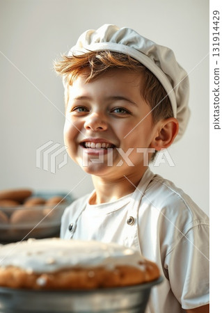 smiling child boy, wearing cooking apron and hat, holding bread. Little baker kid in kitchen setting 131914429