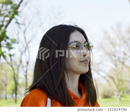 A beautiful woman with a bob haircut and sunglasses takes a walk in a city park A beautiful woman with a bob haircut and sunglasses takes a walk in a city park 131914799