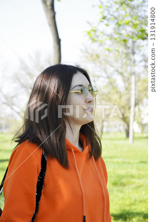 A beautiful woman with a bob haircut and sunglasses takes a walk in a city park A beautiful woman with a bob haircut and sunglasses takes a walk in a city park 131914800