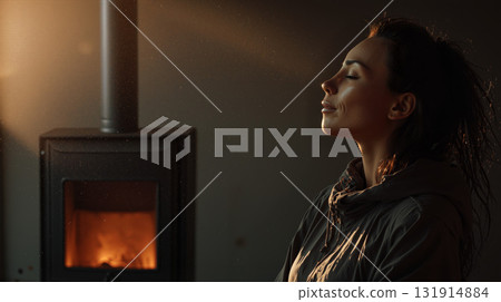 Relaxed woman enjoying warmth by the fireplace in a cozy room during golden hour 131914884