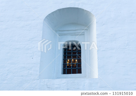 window in the facade of medieval building, behind which a chandelier with candles is visible window in the facade of medieval building, behind which a chandelier with candles is visible 131915010