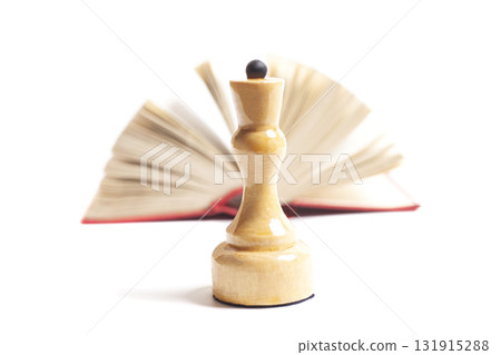 The queen's chess piece in front of an open book The queen's chess piece in front of an open book 131915288