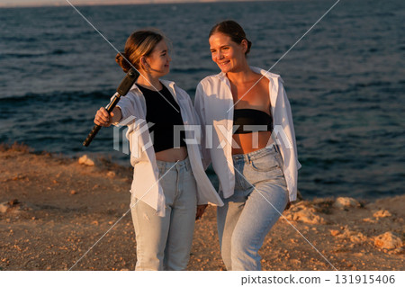 Women Beach Sunset Friends laughing on beach at golden hour. 131915406