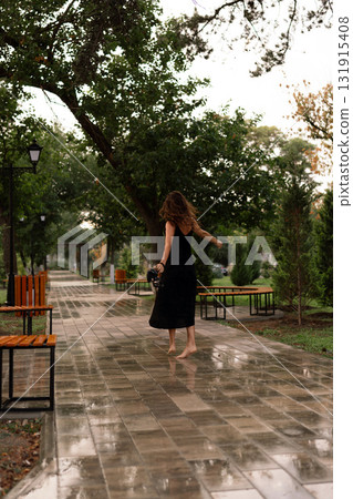 Barefoot woman park, woman walking barefoot on a wet path enjoying a carefree moment 131915408