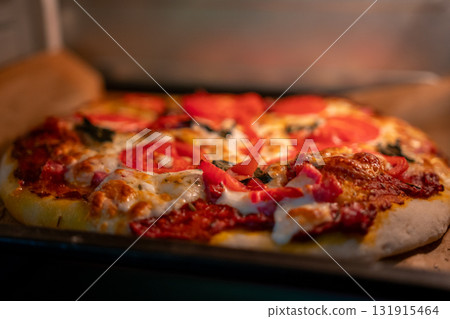 Pizza baking oven. Freshly baked pizza with tomatoes and melting cheese cooking in a hot home oven. Pizza baking oven. Freshly baked pizza with tomatoes and melting cheese cooking in a hot home oven. 131915464