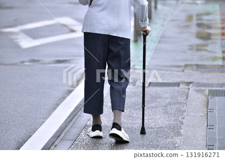Tokyo cityscape in Japan: Aging society... An elderly person with an umbrella in his left hand and a cane in the rain... = Yokohama city on the 11th 131916271