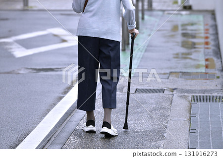 Tokyo cityscape in Japan: Aging society... An elderly person with an umbrella in his left hand and a cane in the rain... = Yokohama city on the 11th Tokyo cityscape in Japan: Aging society... An elderly person with an umbrella in his left hand and a cane in the rain... = Yokohama city on the 11th 131916273