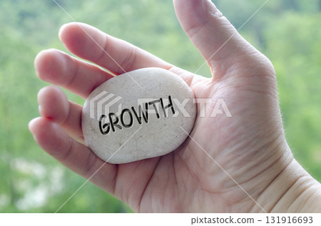 Hand holding a white stone with GROWTH text engraved on it, symbolizing life purpose of learning, evolution, and progress Hand holding a white stone with GROWTH text engraved on it, symbolizing life purpose of learning, evolution, and progress 131916693