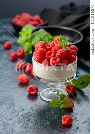Panna cotta with fresh raspberries in a clear bowl. 131916876