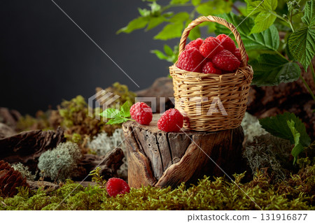 Small wicker basket filled with fresh, ripe raspberries. 131916877