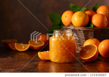 Orange jam and fresh fruits on a brown table. 131916887